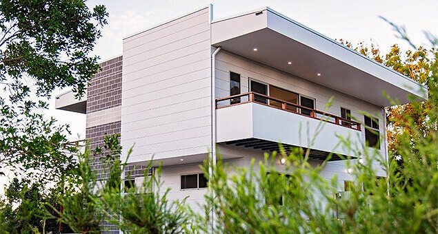 Home designed by Design Direct seen through green shrubbery